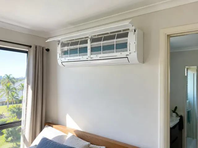 Clean split system with open front panel and visible filters on a bedroom wall in a modern home in Varsity Lakes